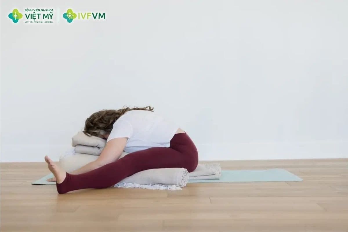Tư thế ngồi gập người chân dang rộng có gối đỡ hỗ trợ thư giãn vùng hông, đùi trong và lưng dưới